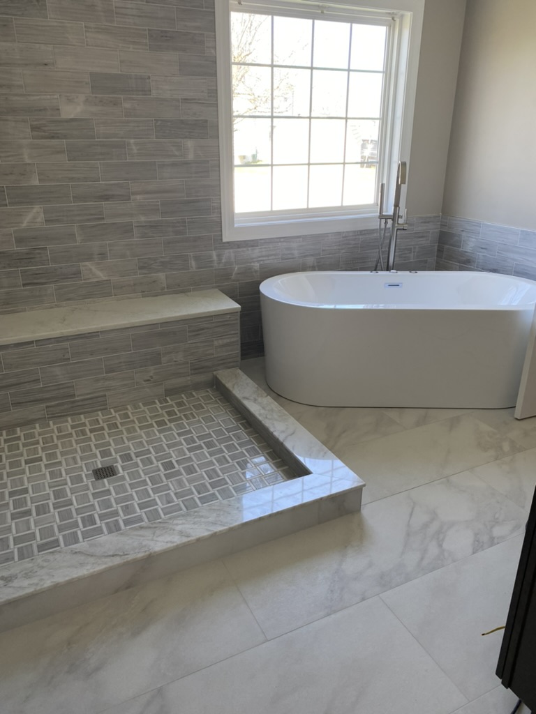 Bathroom vanity with stone top, black fixtures, and wall sconce lighting.