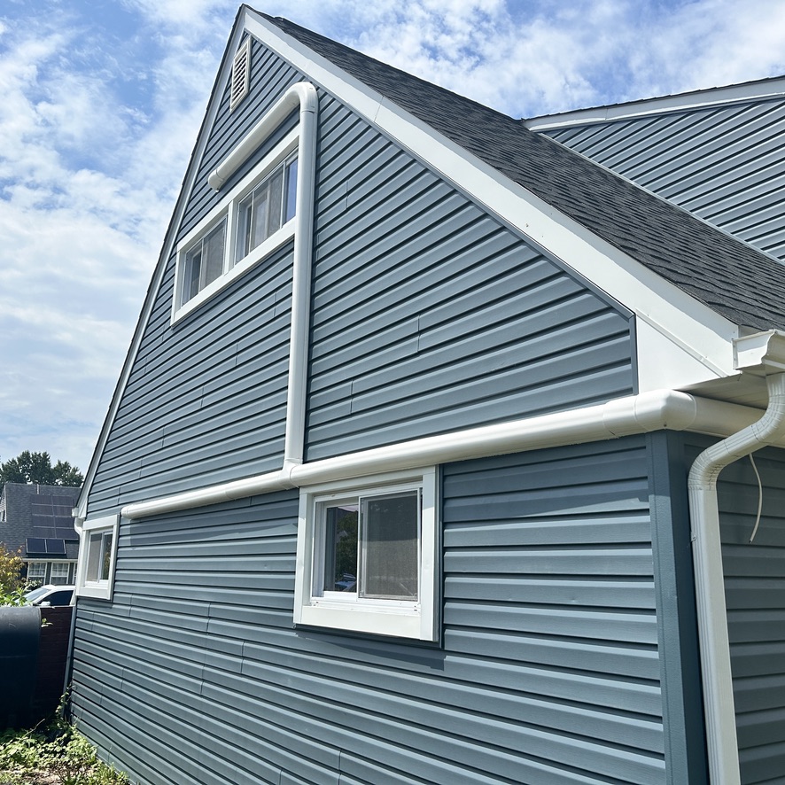 Home exterior with new roofing, siding, and gutters